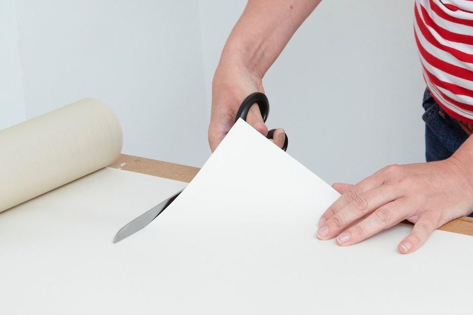 Отрежьте полосу обоев ножницами или оформительским ножом