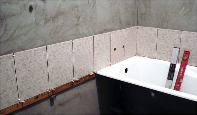 На фото показан пример укладки первого ряда плитки над бортом ванны